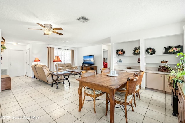 tiled dining space with a textured ceiling and ceiling fan