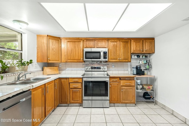 kitchen with appliances with stainless steel finishes, light tile patterned flooring, tasteful backsplash, and sink