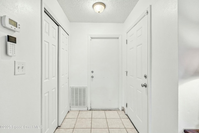 corridor with a textured ceiling and light tile patterned floors