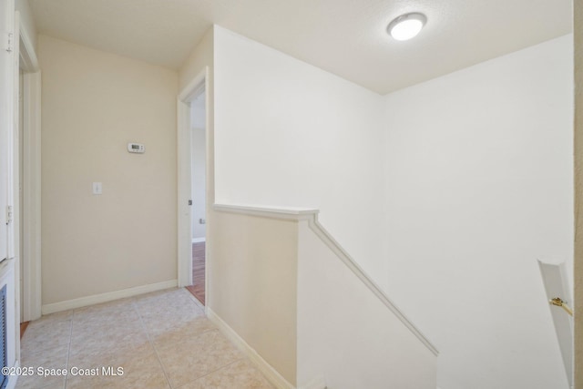 hall with a textured ceiling and light tile patterned floors