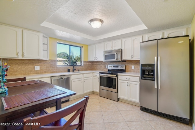 kitchen featuring sink, white cabinetry, a tray ceiling, and appliances with stainless steel finishes