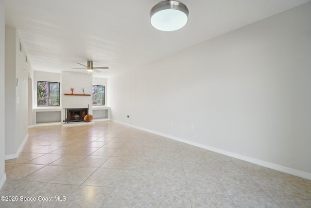 unfurnished living room with ceiling fan, a brick fireplace, and light tile patterned floors