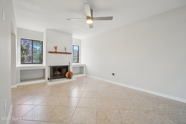 unfurnished living room featuring a brick fireplace, ceiling fan, and light tile patterned floors