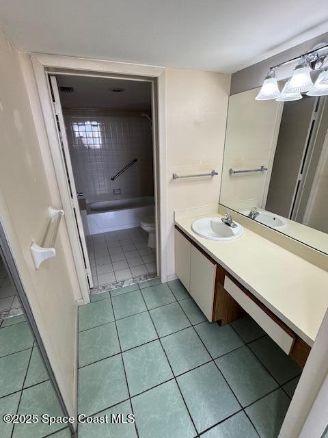 bathroom featuring tile patterned floors, toilet, vanity, and a washtub