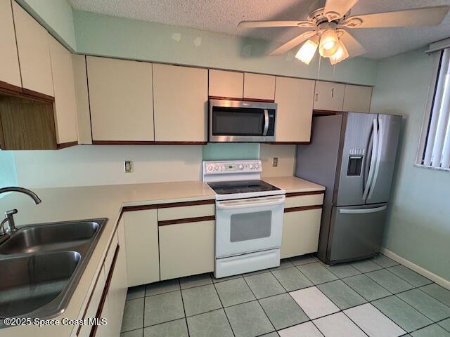 kitchen featuring sink, ceiling fan, stainless steel appliances, a textured ceiling, and light tile patterned flooring