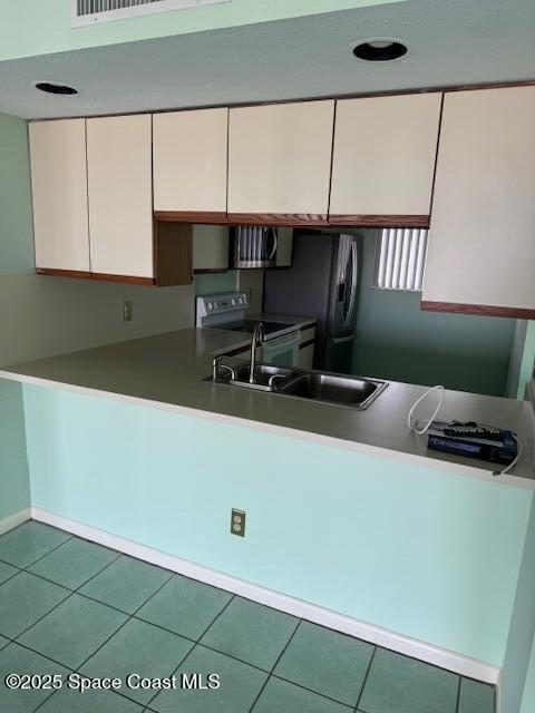 kitchen featuring sink, white electric range oven, and tile patterned floors