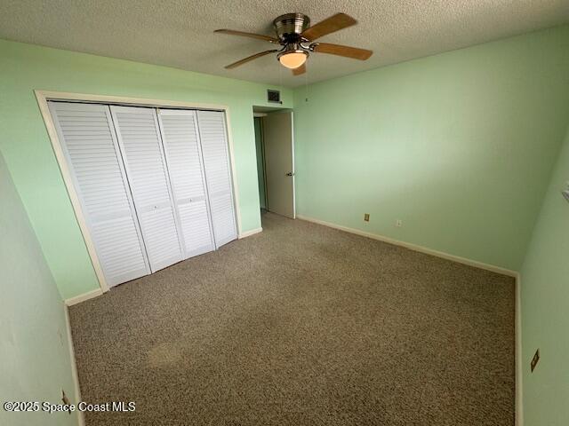 unfurnished bedroom featuring ceiling fan, carpet floors, a textured ceiling, and a closet