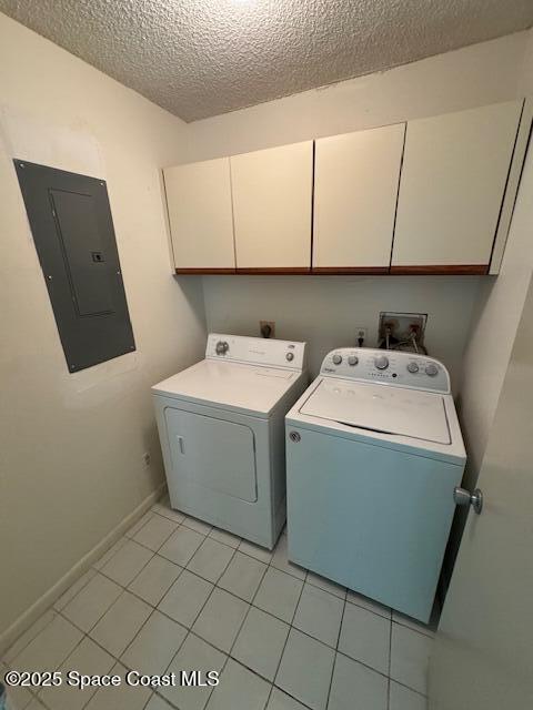 washroom featuring cabinets, separate washer and dryer, a textured ceiling, light tile patterned floors, and electric panel