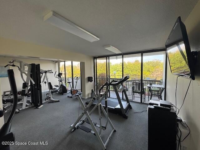 gym featuring a healthy amount of sunlight, a wall of windows, and a textured ceiling