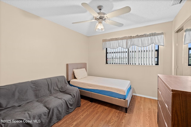 bedroom featuring a textured ceiling, ceiling fan, and light hardwood / wood-style floors