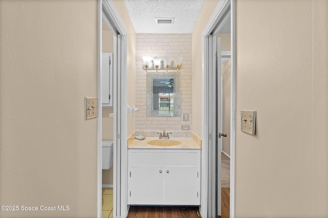 bathroom with a textured ceiling, toilet, and vanity