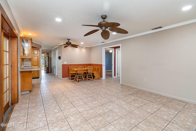 unfurnished living room featuring a textured ceiling, ceiling fan, and crown molding