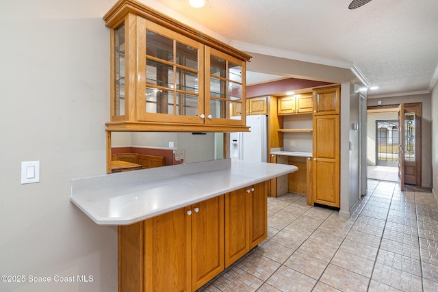 kitchen featuring kitchen peninsula, white refrigerator with ice dispenser, ornamental molding, and a textured ceiling