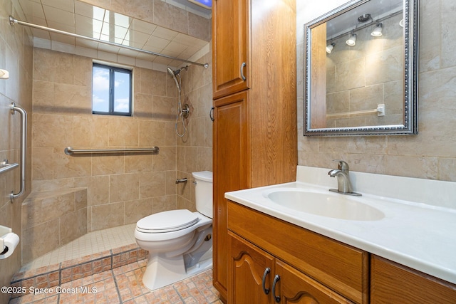 bathroom with toilet, a tile shower, and vanity