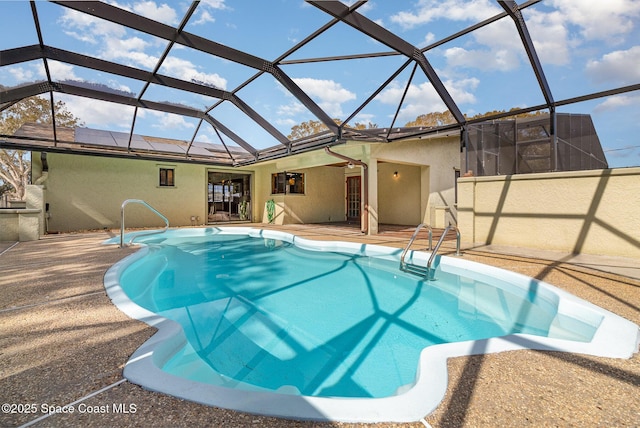 view of pool featuring glass enclosure, a patio area, and ceiling fan