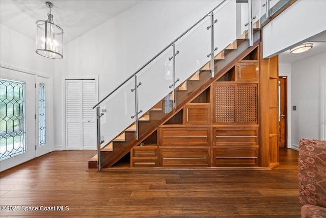 stairway with hardwood / wood-style flooring, a high ceiling, and a chandelier