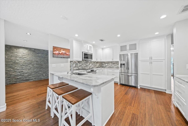 kitchen with white cabinetry, sink, kitchen peninsula, a breakfast bar, and appliances with stainless steel finishes