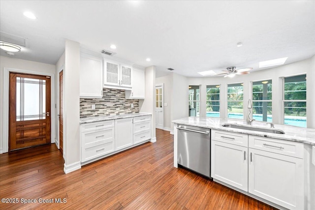 kitchen with a skylight, white cabinetry, sink, and stainless steel dishwasher