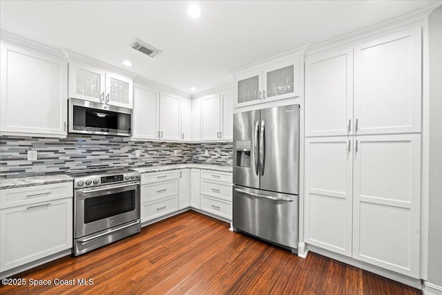 kitchen with white cabinetry, light stone countertops, dark wood-type flooring, decorative backsplash, and appliances with stainless steel finishes