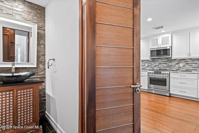 interior space featuring vanity, tasteful backsplash, and hardwood / wood-style flooring