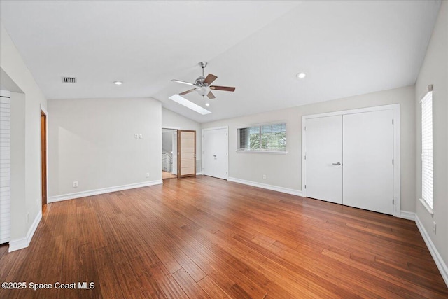 unfurnished bedroom with ceiling fan, vaulted ceiling with skylight, and hardwood / wood-style floors