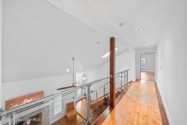 hall with light wood-type flooring and vaulted ceiling