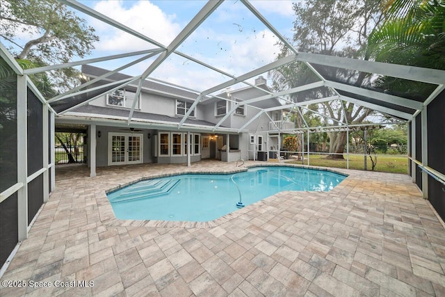 view of pool with a lanai, a patio area, ceiling fan, and french doors