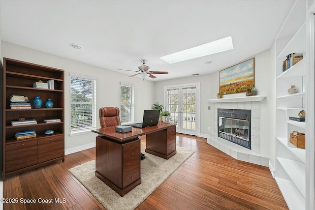 office featuring hardwood / wood-style floors, ceiling fan, a fireplace, and french doors