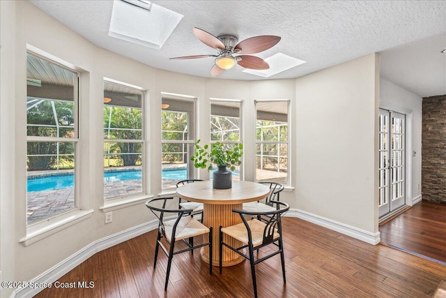 145 Crispin St, Merritt Island, FL 32952 - dining area with a skylight, wood-type flooring, baseboards, a ceiling fan, and a textured ceiling