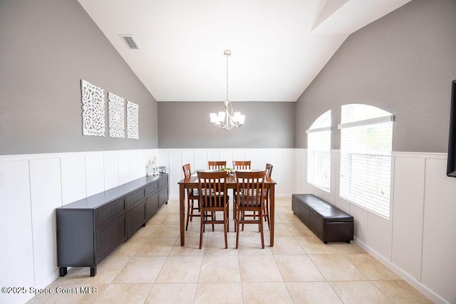 dining area featuring an inviting chandelier, light tile patterned flooring, and vaulted ceiling