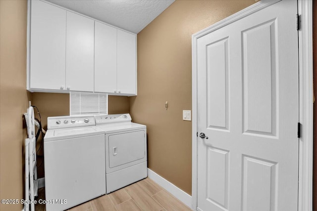 laundry room with washing machine and dryer, a textured ceiling, and cabinets