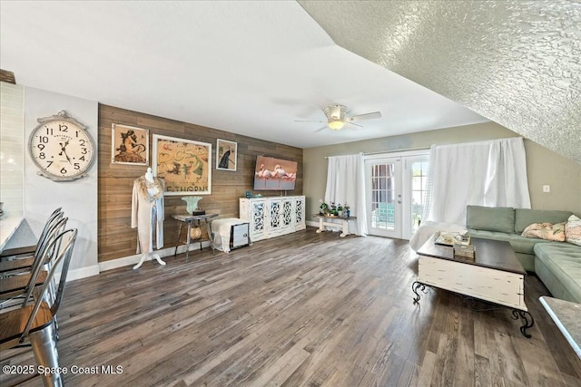 living room with ceiling fan, hardwood / wood-style floors, wood walls, and a textured ceiling