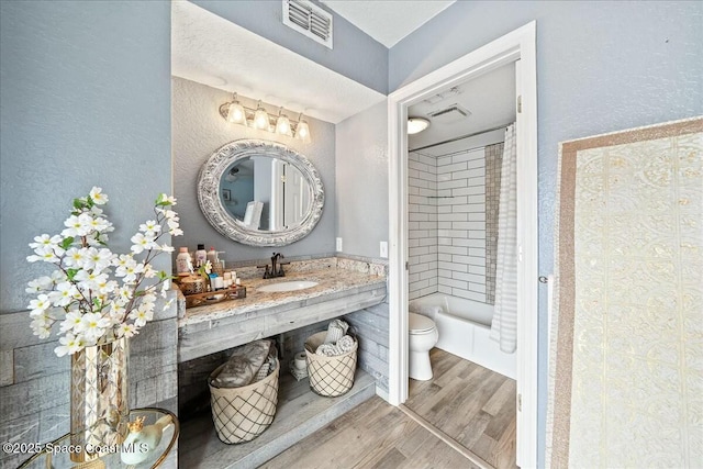 full bathroom with sink, wood-type flooring, shower / bath combo with shower curtain, and toilet