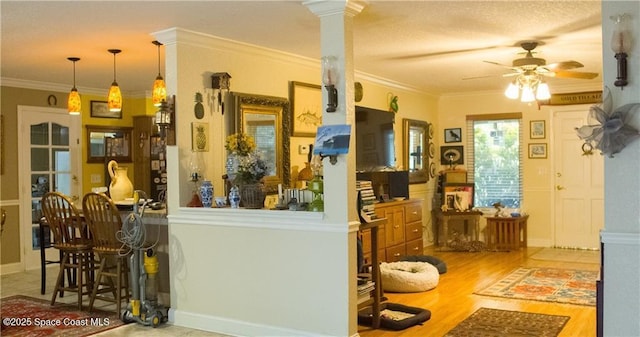 kitchen featuring hardwood / wood-style floors, decorative columns, ceiling fan, and ornamental molding