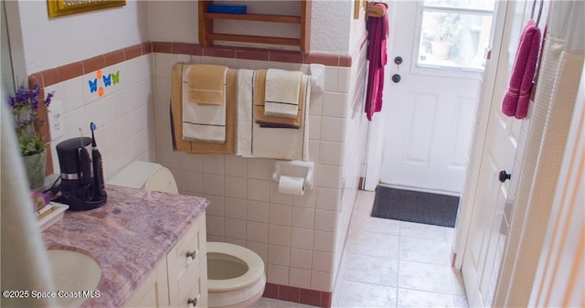 bathroom featuring tile patterned flooring, vanity, tile walls, and toilet