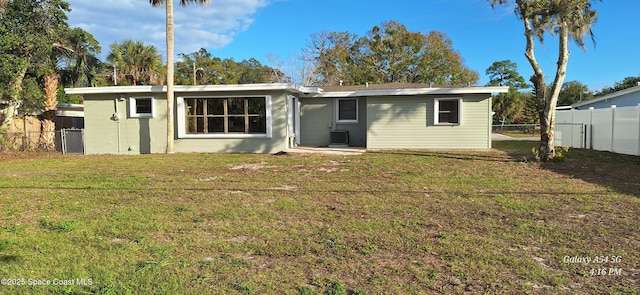 rear view of property with central air condition unit and a yard