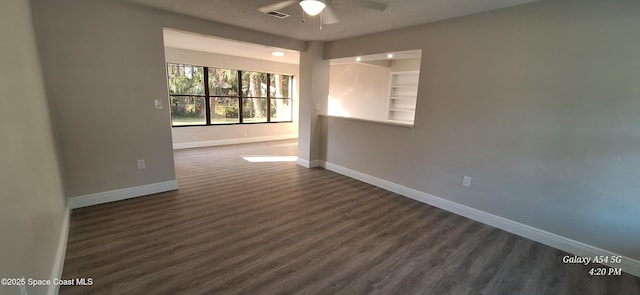 unfurnished room with ceiling fan, built in shelves, and dark hardwood / wood-style flooring