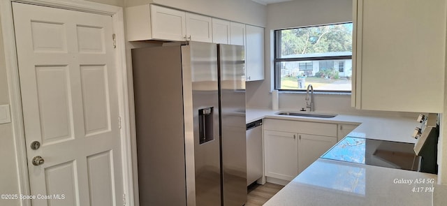 kitchen featuring sink, white cabinetry, appliances with stainless steel finishes, and light wood-type flooring