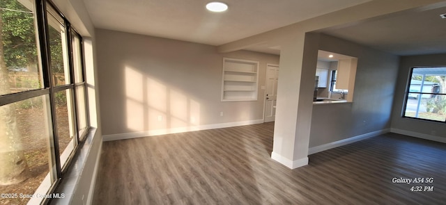 empty room featuring built in shelves and dark hardwood / wood-style floors