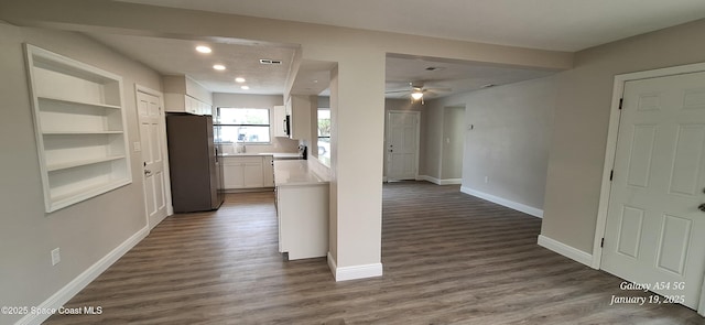 kitchen with built in shelves, dark hardwood / wood-style floors, stainless steel refrigerator, and white cabinetry