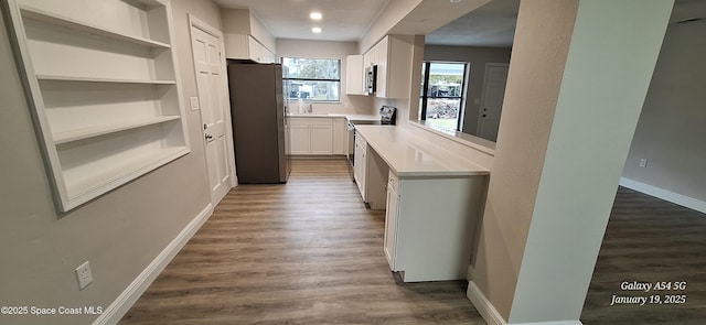 kitchen featuring stainless steel appliances, dark hardwood / wood-style flooring, built in shelves, white cabinets, and sink