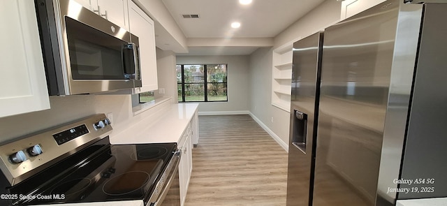 kitchen with white cabinets, appliances with stainless steel finishes, and light hardwood / wood-style flooring