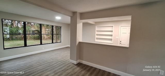 empty room featuring built in features and dark hardwood / wood-style floors