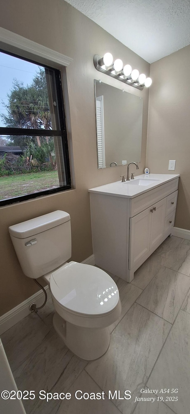 bathroom with a textured ceiling, toilet, and vanity