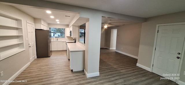 kitchen with white cabinets, built in features, light wood-type flooring, and stainless steel fridge