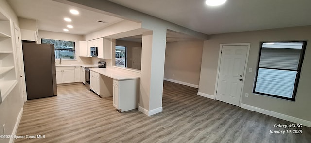 kitchen featuring white cabinets, light wood-type flooring, appliances with stainless steel finishes, and sink