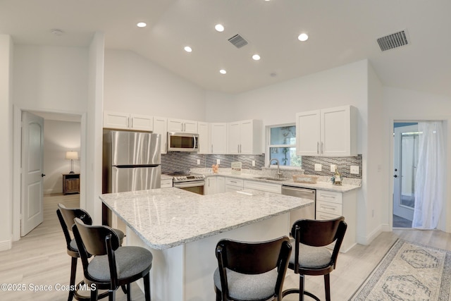 kitchen with a kitchen breakfast bar, white cabinetry, a kitchen island, and appliances with stainless steel finishes