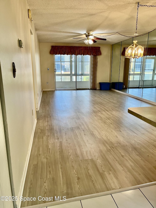 spare room with ceiling fan with notable chandelier, a textured ceiling, and hardwood / wood-style flooring