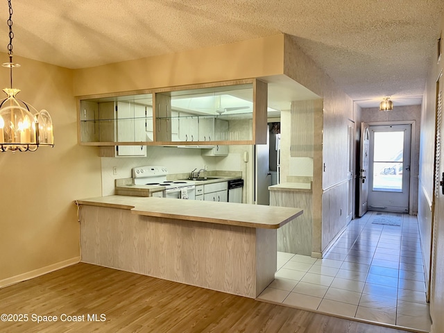 kitchen with a textured ceiling, appliances with stainless steel finishes, kitchen peninsula, and hanging light fixtures