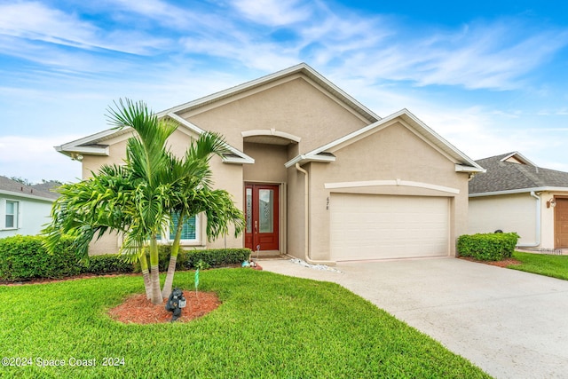 view of front of property featuring an attached garage, driveway, a front yard, and stucco siding